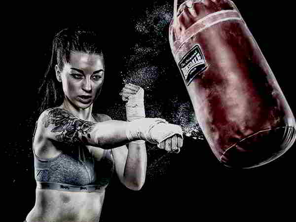 Mujer entrenando con bolsa de boxeo y kickboxing.